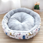 Round pet bed with cartoon animal patterns on a wooden floor.