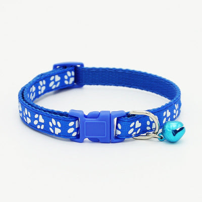 Blue cat collar with white paw prints and a bell on a light gray background