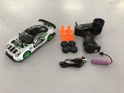 Toy racing car set with remote control, batteries, and cones on a white surface