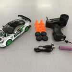 Toy racing car set with remote control, batteries, and cones on a white surface