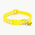 Yellow pet collar with paw prints and a heart-shaped bell on a white background