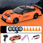 Orange toy car with black details on an orange background, accompanied by remote control, battery, and cones.