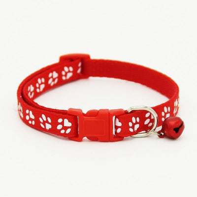 Red cat collar with white paw prints and a bell on a white background