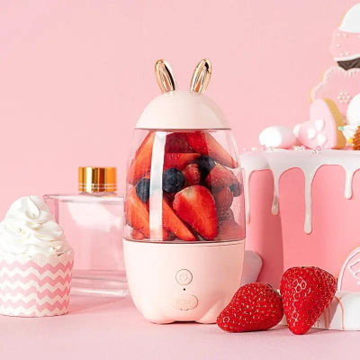 Pink blender with berries on a pink background with a cake and cupcake.