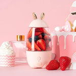 Pink blender with berries on a pink background with a cake and cupcake.