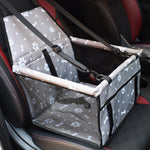 Pet car seat with straps on a car seat, featuring paw print pattern.