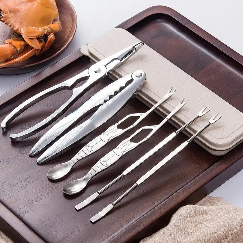 Set of metal seafood tools including tongs and skewers on a wooden tray.