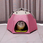 Pink pet tent with a small animal peeking out on a tiled floor.