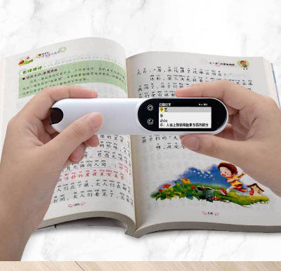 Hand holding a portable device over an open book with text and images.