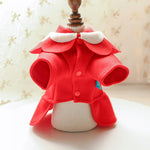 Red felt coat with white collar on a white cushion against a beige background