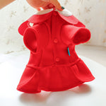Red pet coat with white collar held by a hand on a light background
