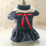 Navy blue pet dress with a red bow on a mannequin against a neutral background