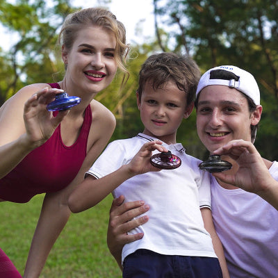 Three people holding yoyos outdoors with greenery in the background