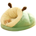 Cat sleeping in a green and beige snail-shaped pet bed on a white background