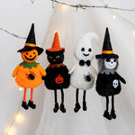 Four Halloween-themed plush toys including a pumpkin, cat, ghost, and witch on a white background with string lights.