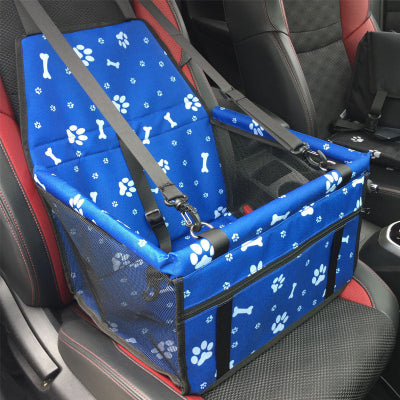 Blue pet seat cover with paw and bone patterns installed in a car.