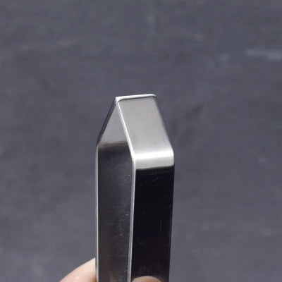 Metallic object held by a hand against a dark background