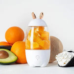 White humidifier with rabbit ears surrounded by oranges and an avocado on a white background