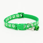 Green cat collar with white paw prints and a bell on a white background