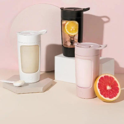 Three portable coffee makers on a pink background with fruits.