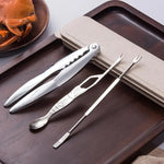 Set of silver plating tongs on a wooden tray with a beige case.