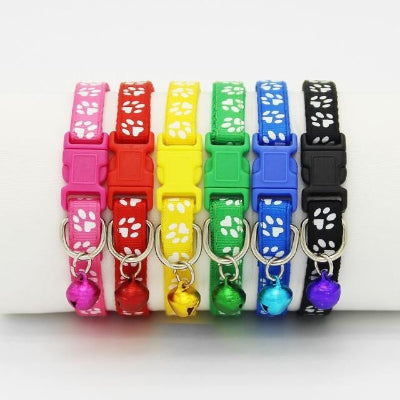 Set of colorful pet collars with paw designs and small bells on a white background
