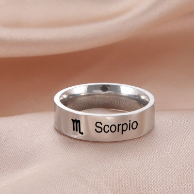 Silver ring with 'Scorpio' and zodiac symbol on a beige fabric background