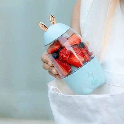 Portable blender with strawberries inside held by a person against a light background