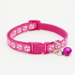 Pink pet collar with white paw prints and a bell on a white background