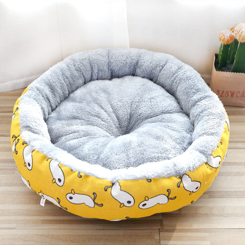 Round pet bed with gray interior and yellow exterior featuring dog patterns on a wooden floor.