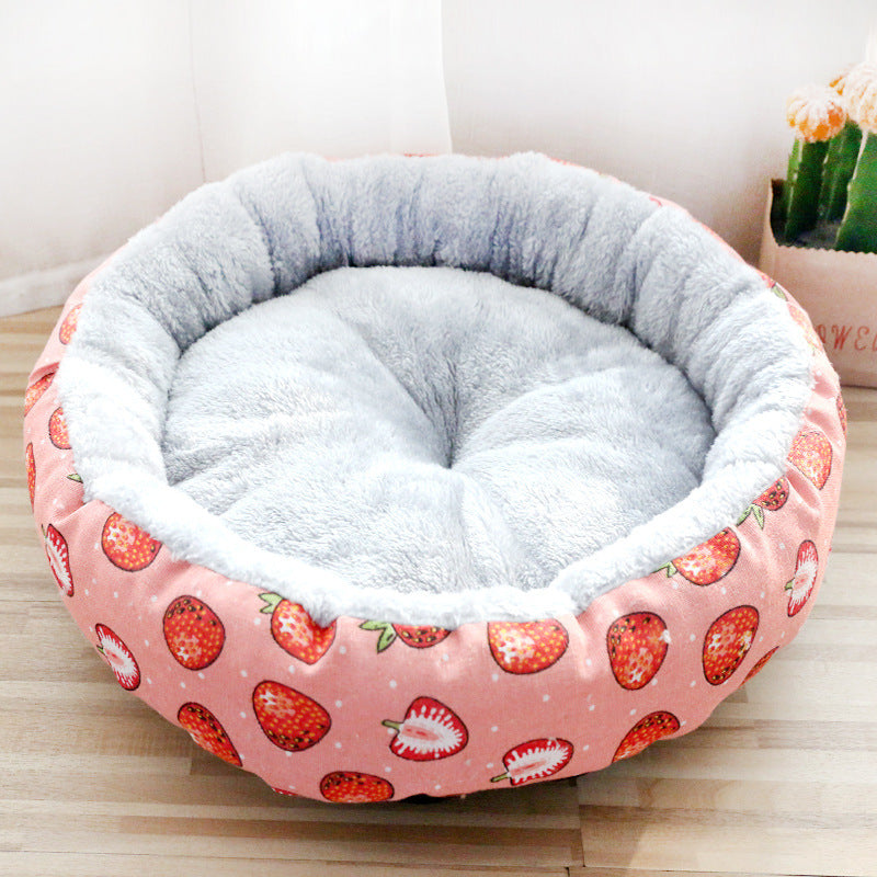 Round pet bed with strawberry pattern on a light wooden floor.