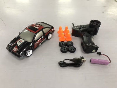 Toy car with remote control, battery, and cones on a white surface