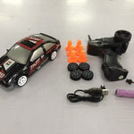 Toy car with remote control, battery, and cones on a white surface