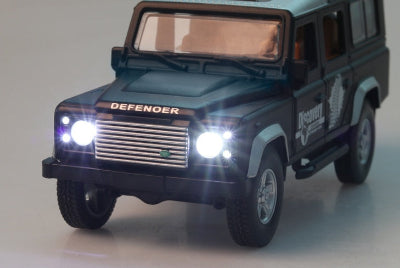 Model of a Land Rover Defender with illuminated headlights on a gray background