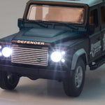 Model of a Land Rover Defender with illuminated headlights on a gray background