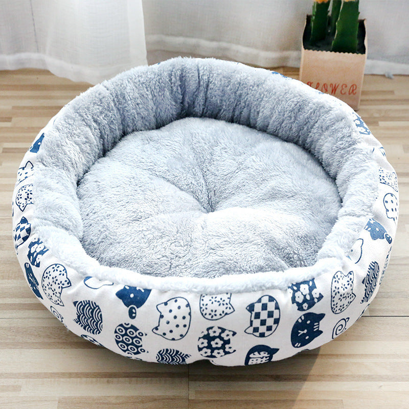Round pet bed with blue and white cat pattern on a wooden floor.