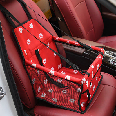 Red pet seat cover with white paw prints on a car seat