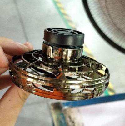 Metallic spinner toy held by a hand with a blurred background