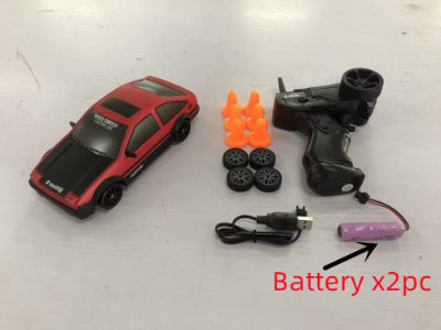 Red toy car with remote control, batteries, and orange traffic cones on a white background