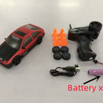 Red toy car with remote control, batteries, and orange traffic cones on a white background