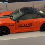 Orange toy car with black accents in a box
