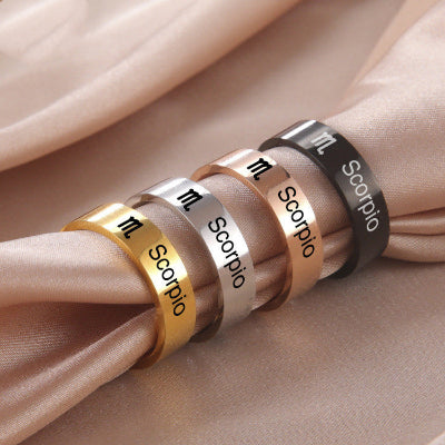 Four Scorpio zodiac sign rings in different colors on a beige fabric background