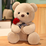 Beige teddy bear with a red rose and black bow on a wooden surface