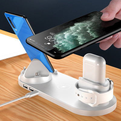 Multi-device charging station with smartphone, tablet, and wireless earbuds on a wooden surface.