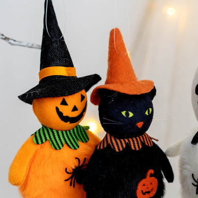 Halloween-themed plush toys, one resembling a pumpkin with a witch hat and the other a black cat with an orange hat, on a white background.