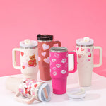 Set of colorful tumblers with various designs on a pink background