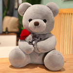 Gray teddy bear with a red bow tie on a wooden surface